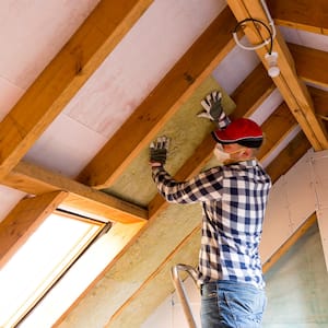 A professional insulating an attic at a house