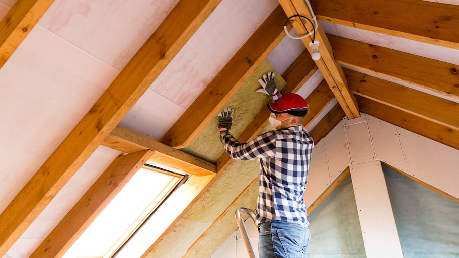 A professional insulating an attic at a house