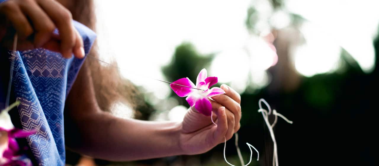 Woman using long needle to thread an orchid