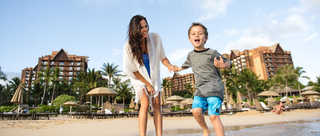 Mother and son on beach with Aulani in the background