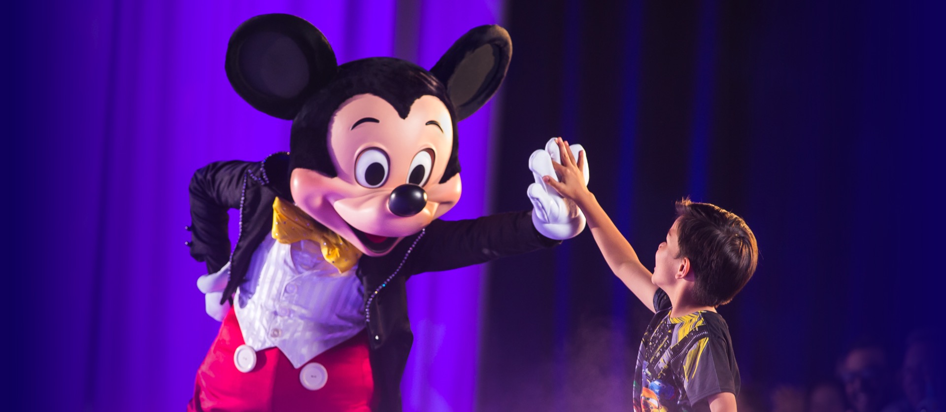 Mickey Mouse high-fives young boy at the show