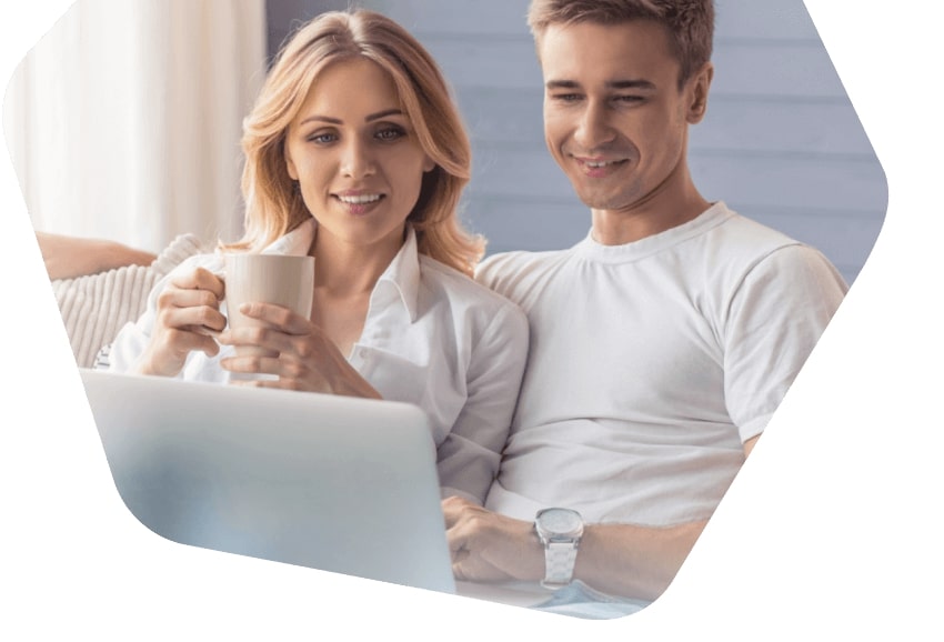 Happy couple smiling while browsing on a laptop