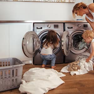 Two kids help mom with the laundry