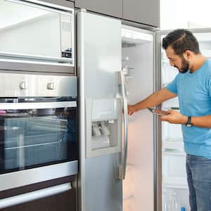 Man in front of the fridge making a shopping list