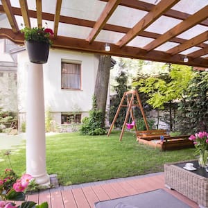 A patio in a backyard with a wooden pergola