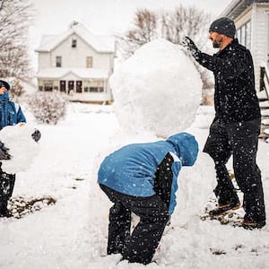 A father and sons build a snowman