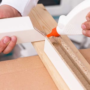 A view of someone using wood glue on a doorframe