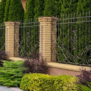 A wrought iron fence between decorative brick columns