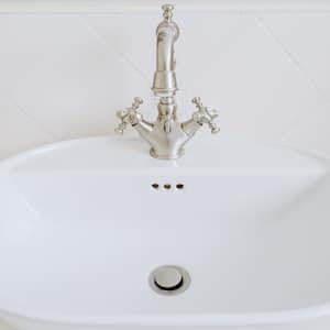 A porcelain bathroom sink with an old style tap