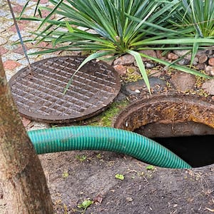 Septic tank with an open cover and green hose for pumping
