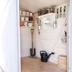 A shed with both doors open with a chair and gardening tools inside