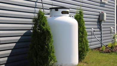 propane tank between two bushes along side of house