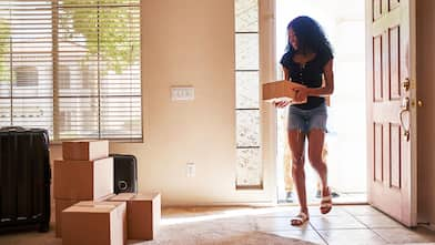 A woman moving in new house carrying a cardboard box