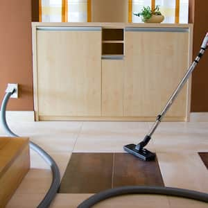 A woman cleaning the living room with a central vacuum