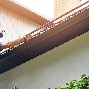 A man installs gutters on a house