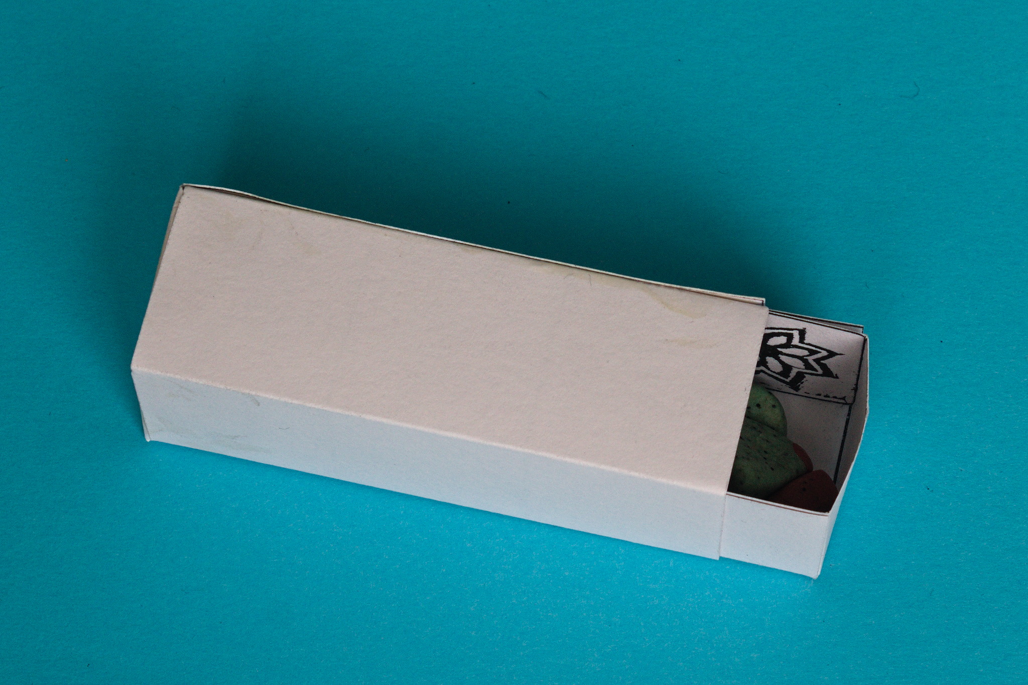 A white box, about 2.5 cm × 2.5 cm × 7.5 cm; a drawer is sliding out of one small end.