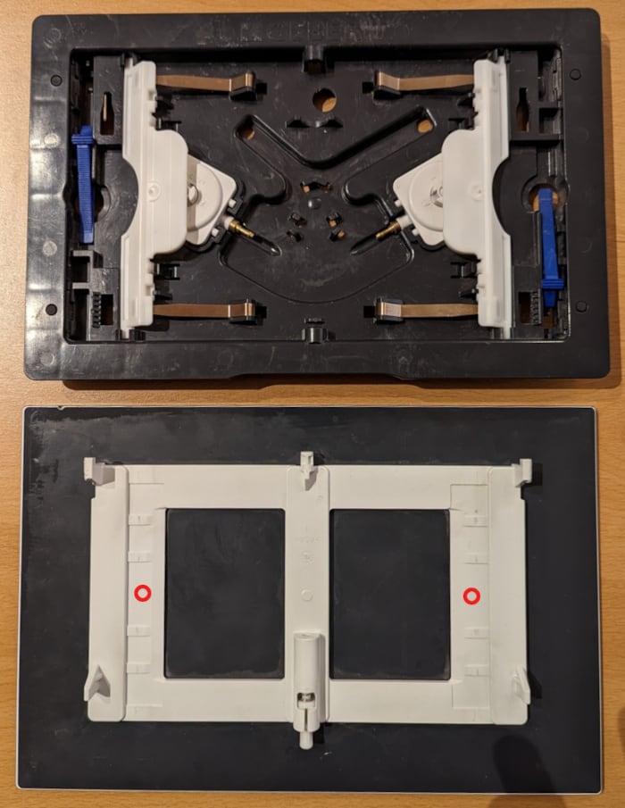 Geberit Sigma 70 flush plate. Top: the mechanism that converts the mechanical press into a hydraulic impulse. Bottom: the back of the plate with the two places where to apply the bumpers.