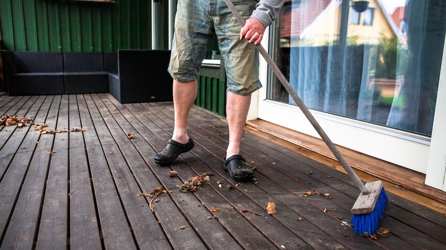 Man sweeping debris off of his deck with a broom