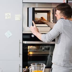 Man removing food from microwave while talking on phone