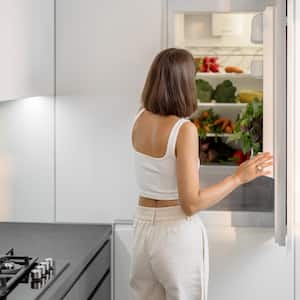 A woman in front of an open fridge in a modern kitchen
