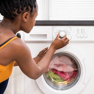 A woman adjusts washing machine settings
