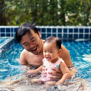 Father and toddler daughter playing in the swimming pool