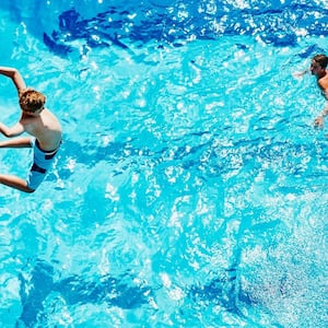 A boy jumping in the pool from a diving board