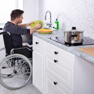 Man in wheelchair washes dishes