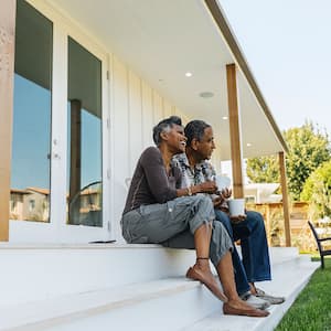 A couple sit on the back porch of a house