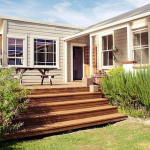 A wooden deck with outdoor furniture in the backyard of a house