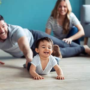 Baby excitedly crawling across the floor away from parents