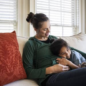 Mother and daughter on couch in front of window with blinds