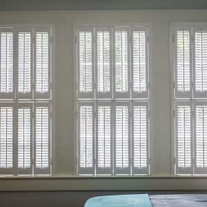 Three large windows with estate shutters in a bedroom