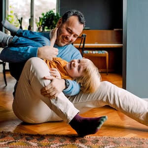 father playing with child in home