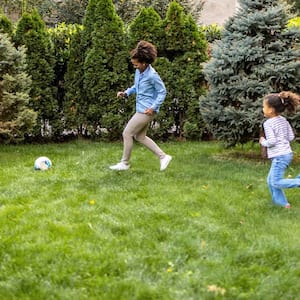 Mother and daughter playing soccer in the yard