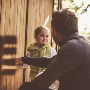 Father and daughter in front of wood fence