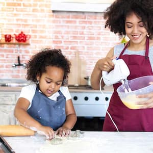 Mother and daughter in the kitchen mixing dough to make cookies