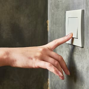 A woman’s hand turning off a light switch