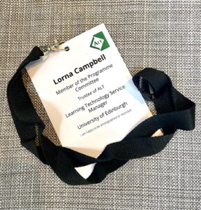 Photograph of an ALT Conference delegate badge, white card with black text against a grey background.