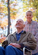 Veteran in a wheelchair pushed by grandson