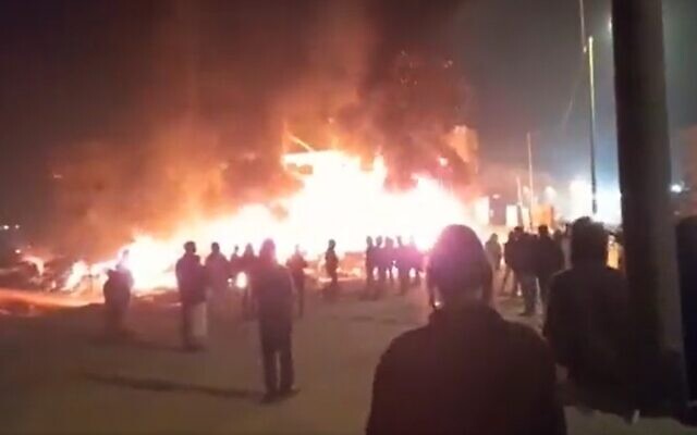 Settlers pray as cars and homes burn in the West Bank town of Huwara on February 26, 2023. (Screenshot/Twitter; used in accordance with Clause 27a of the Copyright Law)