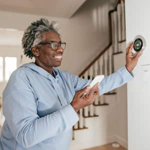 Woman adjusting wall thermostat