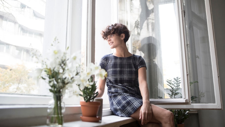 woman looking at phone near open window