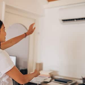 A woman turning on an air conditioner