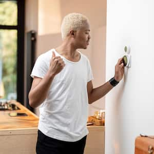 A young man turning on the thermostat