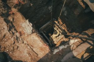 A WORKER DESCENDS INTO A DEEP MINE SHAFT