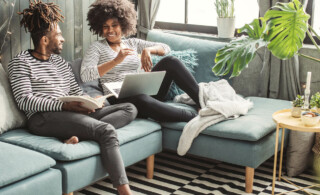 couple laughs in comfortable home while doing research