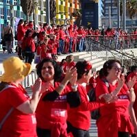 Hundreds of women dressed in red mark International Women's Day and demonstrate against the government's planned judicial overhaul, on the beach in Tel Aviv, March 8, 2023. (Tomer Neuberg/Flash90)