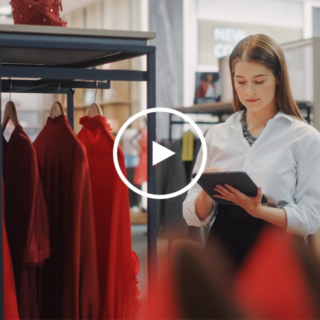 Image of a female sales associate looking at a tablet in a retail/fashion store.