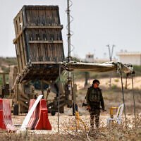 Illustrative: An Israeli soldier stands near an Iron Dome air defense system battery, deployed in southern Israel on August 6, 2022. (Menahem Kahana/AFP)